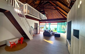A spacious living area with a staircase, a sofa set, and a TV.