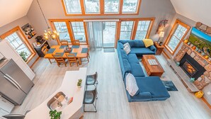 A spacious loft apartment with a kitchen, dining area, and living room. It features large windows, a fireplace, and a high ceiling. - Hot Tub, Sauna & Game Room, Sleeps 8, Pet OK - Near Camelback (Tannersville)