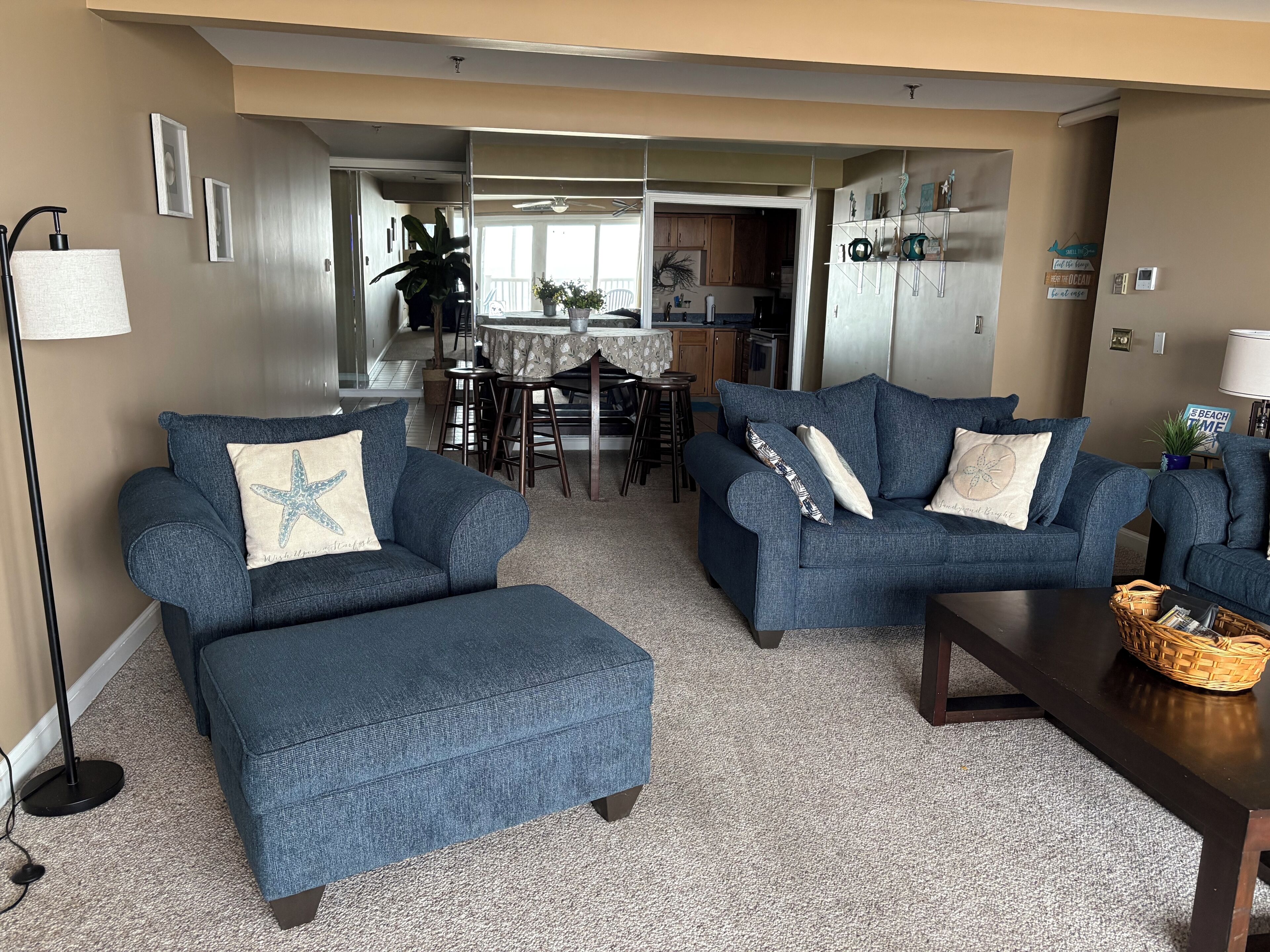 Ein Wohnzimmer mit zwei blauen Sofas, einem Couchtisch und einer Küche im Hintergrund.
