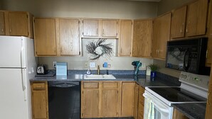 Una cocina con gabinetes de madera, un refrigerador blanco, lavavajillas, estufa y microondas.