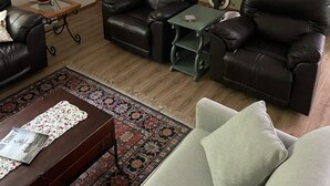 A living room with two leather sofas, a coffee table, a rug, and a door.