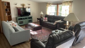 A living room with a sofa, armchair, and a TV on a stand.