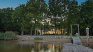 Une propriété au bord du lac, dotée d’une jetée en bois, d’un mur en pierre et d’une maison à l’intérieur bien éclairé.