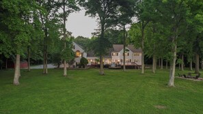 A two-story house with a covered patio and a lawn.