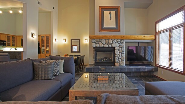 Una sala de estar con chimenea de piedra, un sofá, una mesa de centro y un televisor.