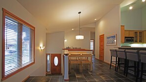 Una cocina amplia con una isla central, sillas de madera y una barra con taburetes.