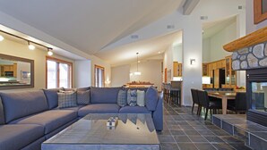 Una sala de estar moderna con un sofá modular, una mesa de centro de vidrio y un comedor con mesa y sillas de madera.