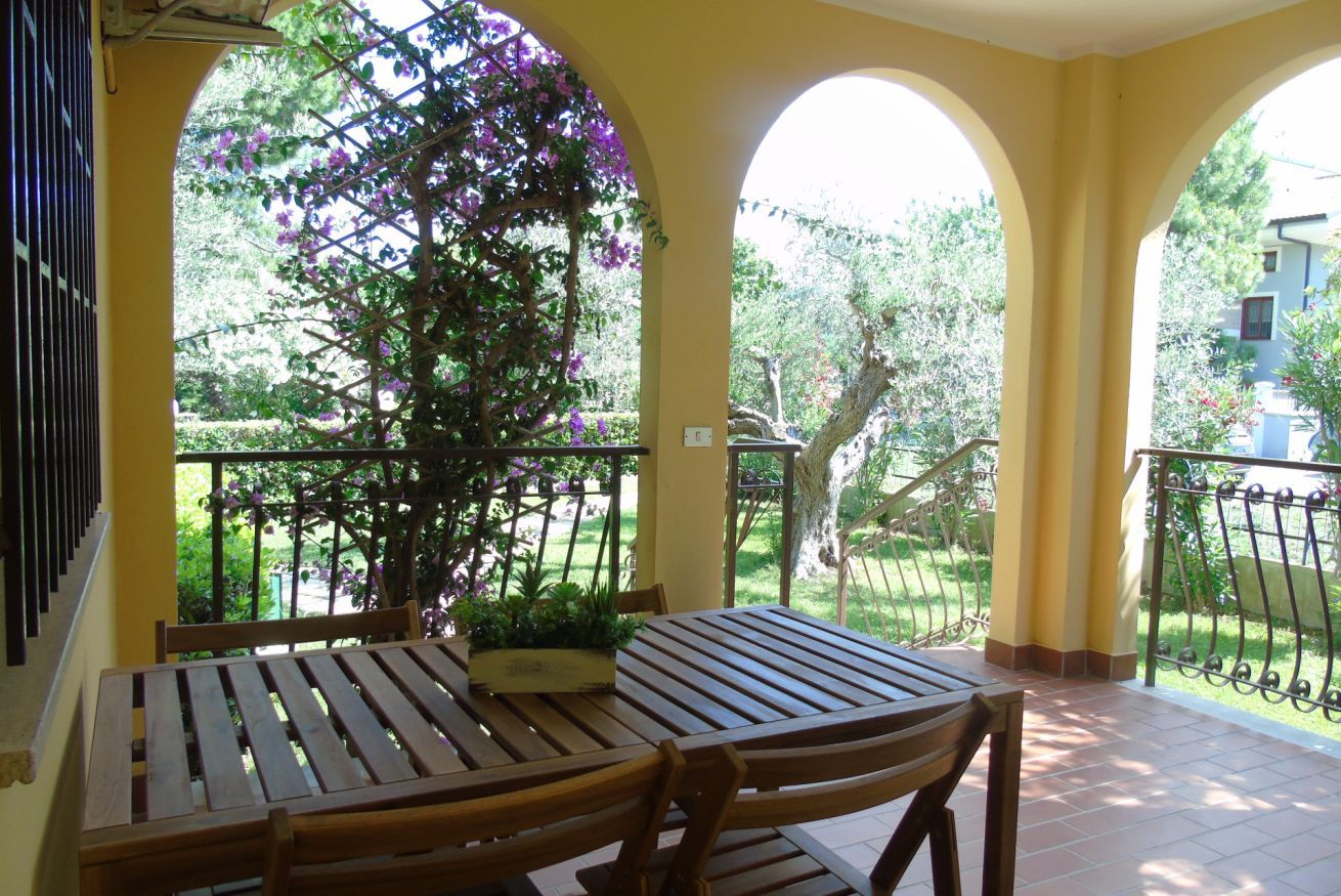 Un espace extérieur aménagé, abrité et doté d’une table et de chaises, entouré d’une rambarde et offrant une vue sur la verdure.