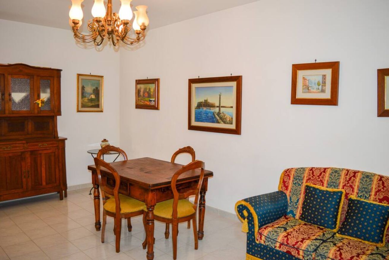 Un'area pranzo con un tavolo e sedie in legno, un divano e quadri appesi al muro.