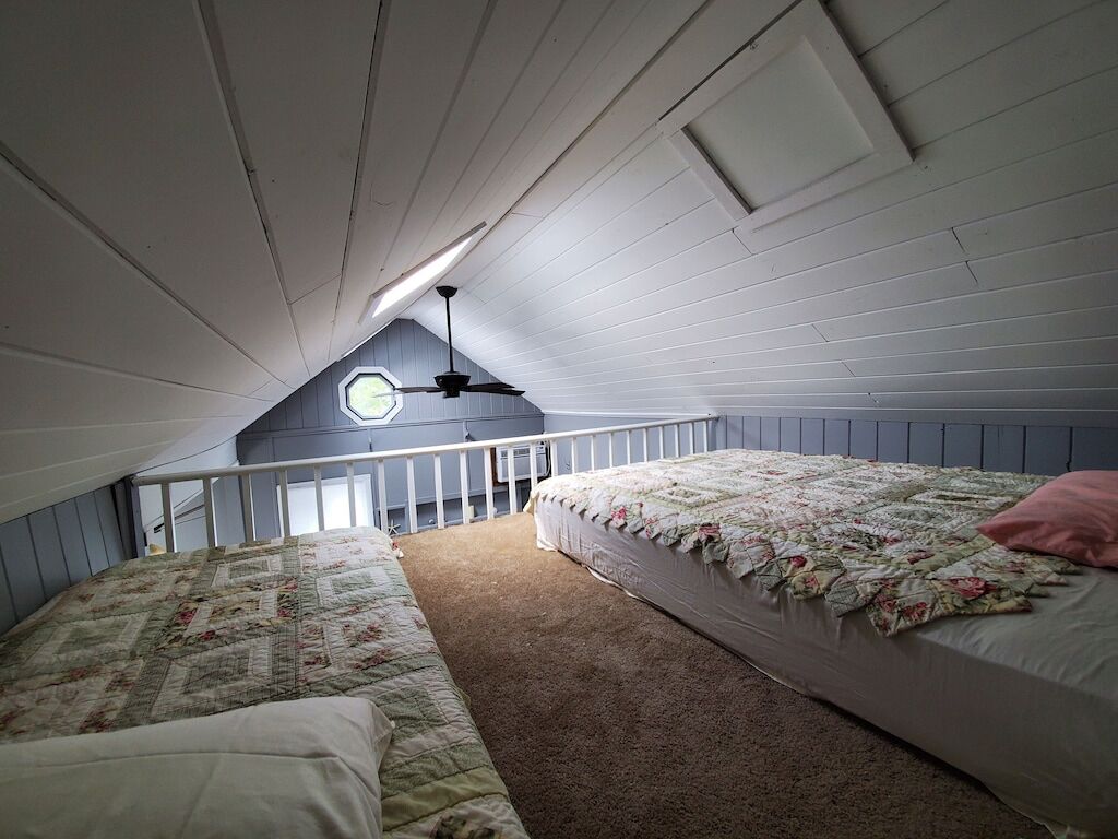 A bedroom with two beds, a ceiling fan, and a window.