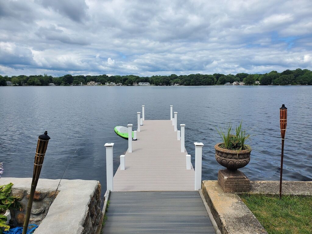 Une jetée en bois qui s’avance sur un lac paisible, sous un ciel nuageux.