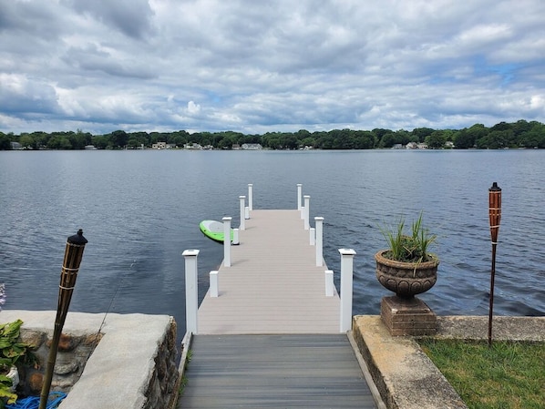 A wooden pier leading into a calm lake with a cloudy sky.