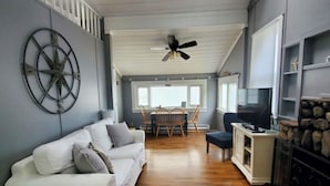 Ein großzügiger Wohnbereich mit einem weißen Sofa, Holzböden und einem Deckenventilator.