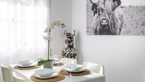 Een eettafel gedekt met witte borden, kommen en wijnglazen, een decoratieve vaas, en een zwart-witfoto van een stier.