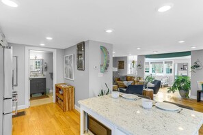 A modern kitchen with a marble countertop, wooden cabinets, and a built-in oven. - Cloud Break (Newburyport)