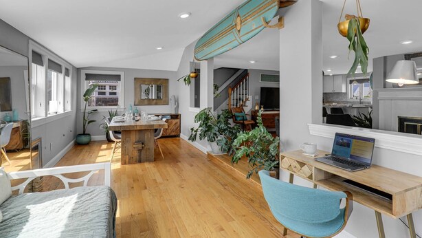 A spacious living area with a wooden dining table, a sofa, and a laptop on a desk. - Cloud Break (Newburyport)