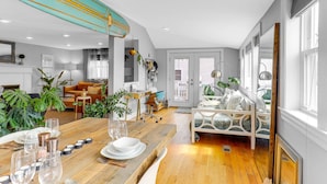 A modern living room with a wooden dining table set for a meal, a sofa, and a bed with a unique design. - Cloud Break (Newburyport)