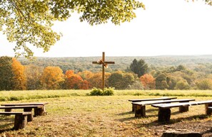 A cross in a natural setting with picnic tables.