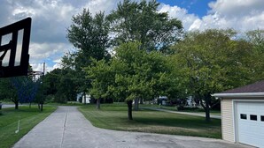 A residential driveway with a basketball hoop, a lawn, and a garage.