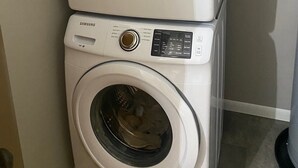 A stacked washer and dryer unit with a control panel and a small window on the top unit.