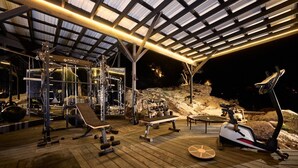 An outdoor gym with exercise equipment, a wooden deck, and a metal roof structure. - Paradise Ranch Inn- Infinite House Hot Tub,Sauna. (Three Rivers)