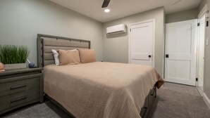 A bedroom with a bed, a nightstand, a ceiling fan, an air conditioning unit, and a door. - Sweet and Spacious Stay Two Blocks from Wildwood's Best Beaches (Wildwood)