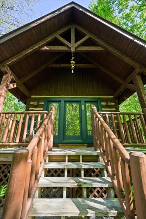A wooden cabin with a green door, a wooden staircase, and a wooden railing. - Cozy 2BR cabin in Wears Valley - your perfect mountain retreat with Hot tub! (sevierville)
