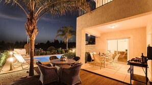 An outdoor patio with wicker furniture, a pool, and a stone wall. - 3 Bedroom Villa with Private Pool and Free Car (Paphos)