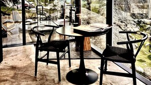 A modern dining area with a round table and two chairs, large windows offering a view of a rocky landscape. - Paradise Ranch Inn- Limitless House Hot Tub,Sauna. (Three Rivers)