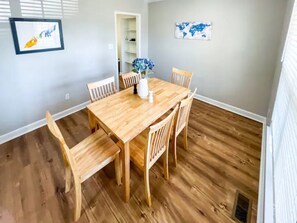 A dining area with a wooden table and chairs, a vase with flowers, and a world map on the wall.