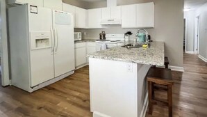 A kitchen with white cabinets, a granite countertop, and a wooden floor. - Cozy Renovated Home 1 mile to DT w/ Fenced in Yard (Raleigh)