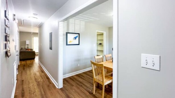 A hallway with wooden flooring leading to a dining area with a table and chairs. - Cozy Renovated Home 1 mile to DT w/ Fenced in Yard (Raleigh)