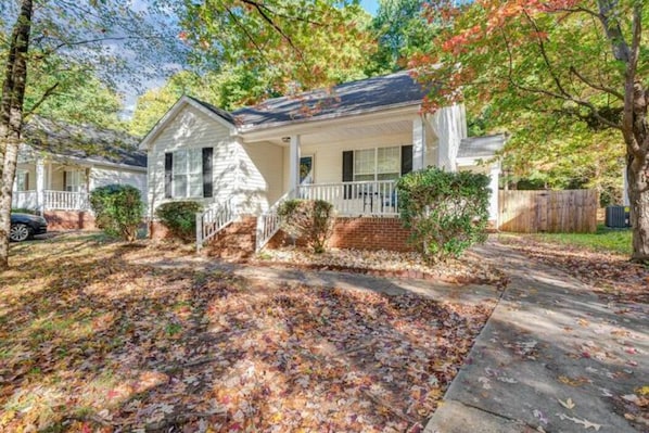A single-story house with a front porch, a brick foundation, and a driveway.