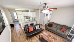 A spacious living room with a sofa and a coffee table, a grey couch, and a ceiling fan. - Cozy Renovated Home 1 mile to DT w/ Fenced in Yard (Raleigh)