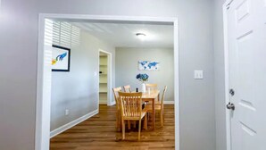 A hallway with wooden flooring leading to a dining area with a table and chairs. - Cozy Renovated Home 1 mile to DT w/ Fenced in Yard (Raleigh)
