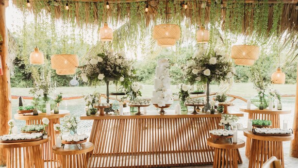 A rustic outdoor wedding setup with wooden tables, hanging lanterns, and floral arrangements. - VENUE EVENTS Cbc Farms 100 person (Okeechobee)