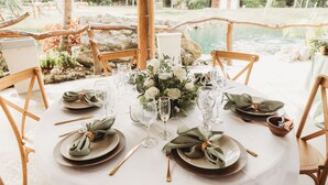 A round table set for six with white tablecloth, green napkins, and a floral centerpiece. - VENUE EVENTS Cbc Farms 100 person (Okeechobee)