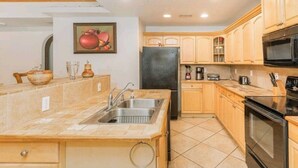 A kitchen with wooden cabinets, a black refrigerator, a stove, and a sink. - VENUE EVENTS Cbc Farms 100 person (Okeechobee)