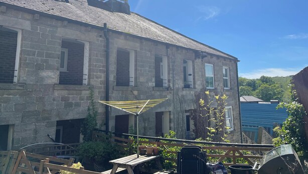 A stone building with multiple windows and a weather vane on the roof.