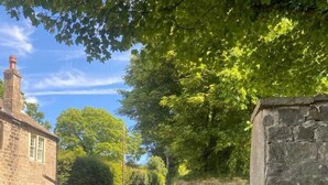 A stone sign with 'SUMMERBRIDGE' inscribed on it, located beside a road with a stone wall and a building in the background.