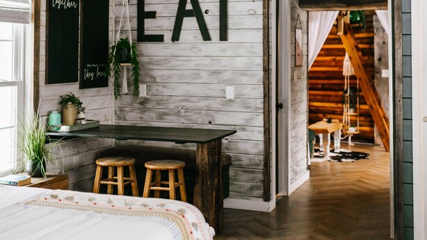 Une pièce rustique comprenant un lit, un coin bar et un escalier menant à un autre niveau.