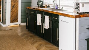 Une cuisine avec un plan de travail en bois, un évier et un réfrigérateur blanc.