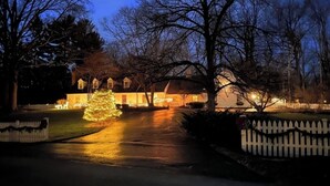 A residential street at dusk with houses on either side, a white picket fence, and a lit Christmas tree in the foreground. - Fox Knoll 1-Studio-Sleeps 2-Beautiful Setting! Indy 500! Grand Park, Concerts! (Indianapolis)