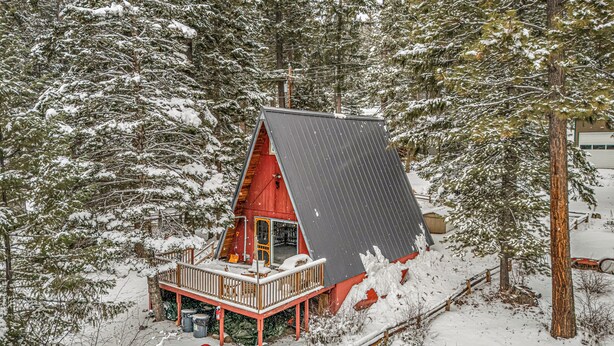 A cabin with a sloped roof, surrounded by snow-covered trees.