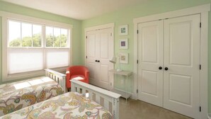 A bedroom with two beds, a red chair, a white desk, and a white wardrobe. - The Nest - The Perfect Asheville Getaway; Pet Friendly!, 10 Mins to Downtown (Asheville)