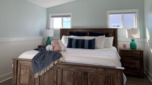 A bedroom with a wooden bed, two bedside tables with lamps, and a ceiling fan. - Newly renovated 3BR/3BA w king bed, linens, towels & views! 🌞 (Surf City)