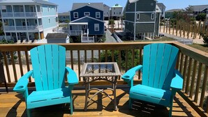 A wooden deck with turquoise Adirondack chairs and a glass table. - Newly renovated 3BR/3BA w king bed, linens, towels & views! 🌞 (Surf City)