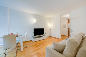 A modern living room with a flat-screen TV, a white dining table, and a beige sofa. - Locarno best place, Locarno, Switzerland (Locarno)