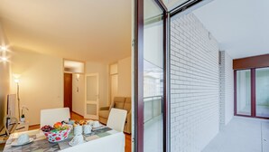 A modern living room with a glass door leading to a balcony, a dining area with a table set for two, and a sofa. - Locarno Best Place near Piazza Grande and Lake, Locarno, Switzerland (Locarno)