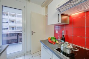 Une cuisine avec un plan de travail recouvert de carreaux rouges, une cuisinière, une casserole et une bouteille de vin posée sur le comptoir.